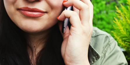 Bottom half of a woman's face while she is one the phone.