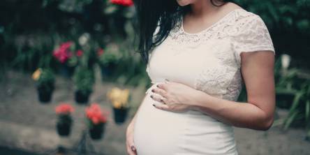 Pregnant woman holding her bump, looking down at it and smiling.